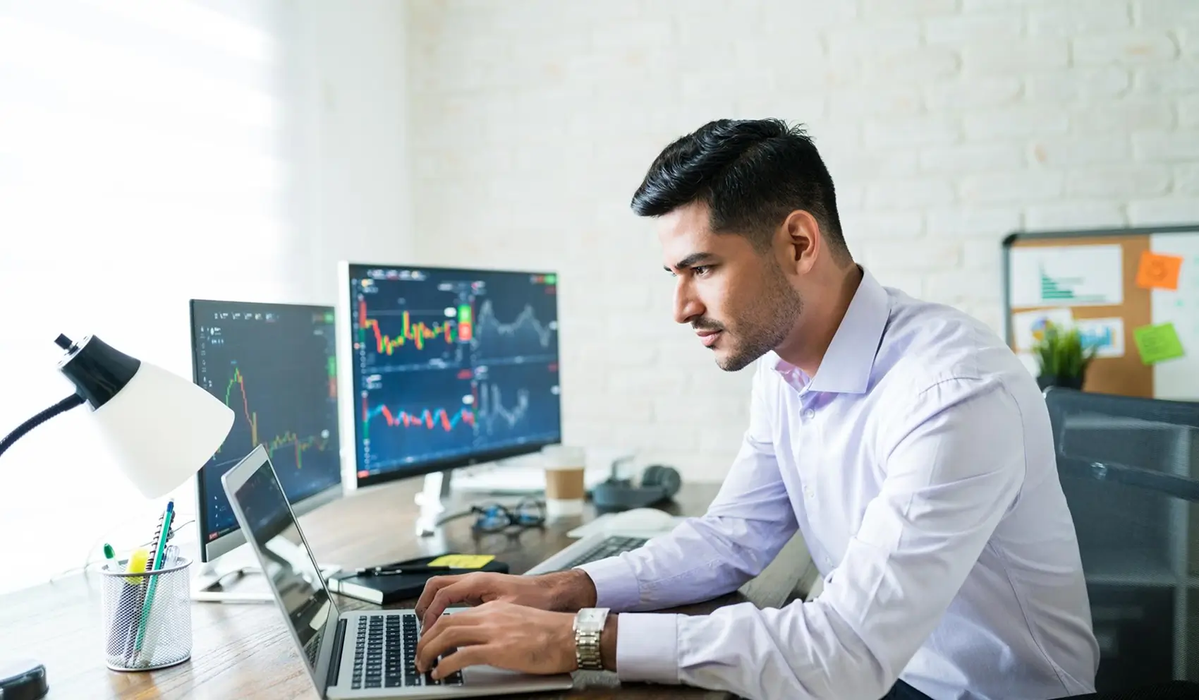 A professional trader working on a laptop in a modern office setup, analyzing forex market charts displayed on multiple monitors. Blog post banner for 'What is Forex Market' by SRFX Global.
